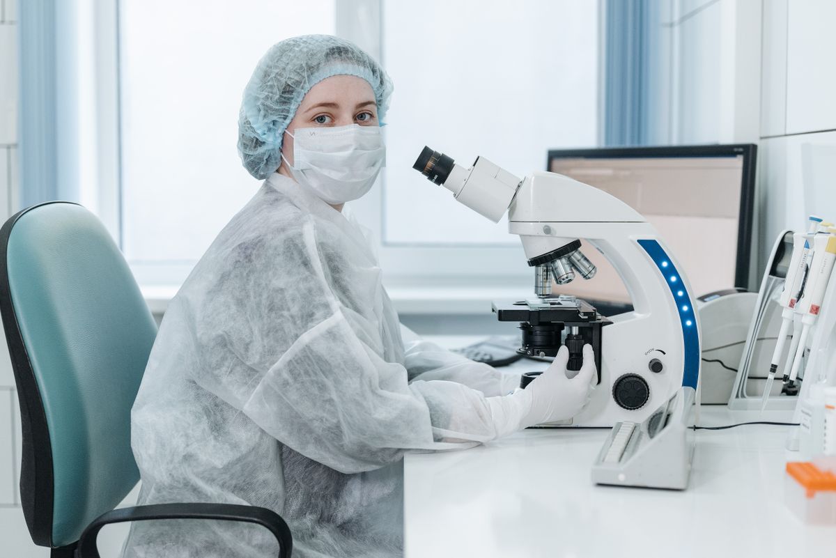 Laboratory technician examining samples with a trinocular microscope