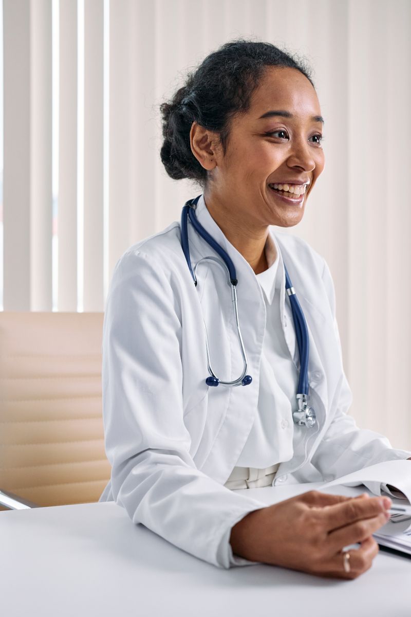Portrait of a smiling physician at her desk with a stethoscope