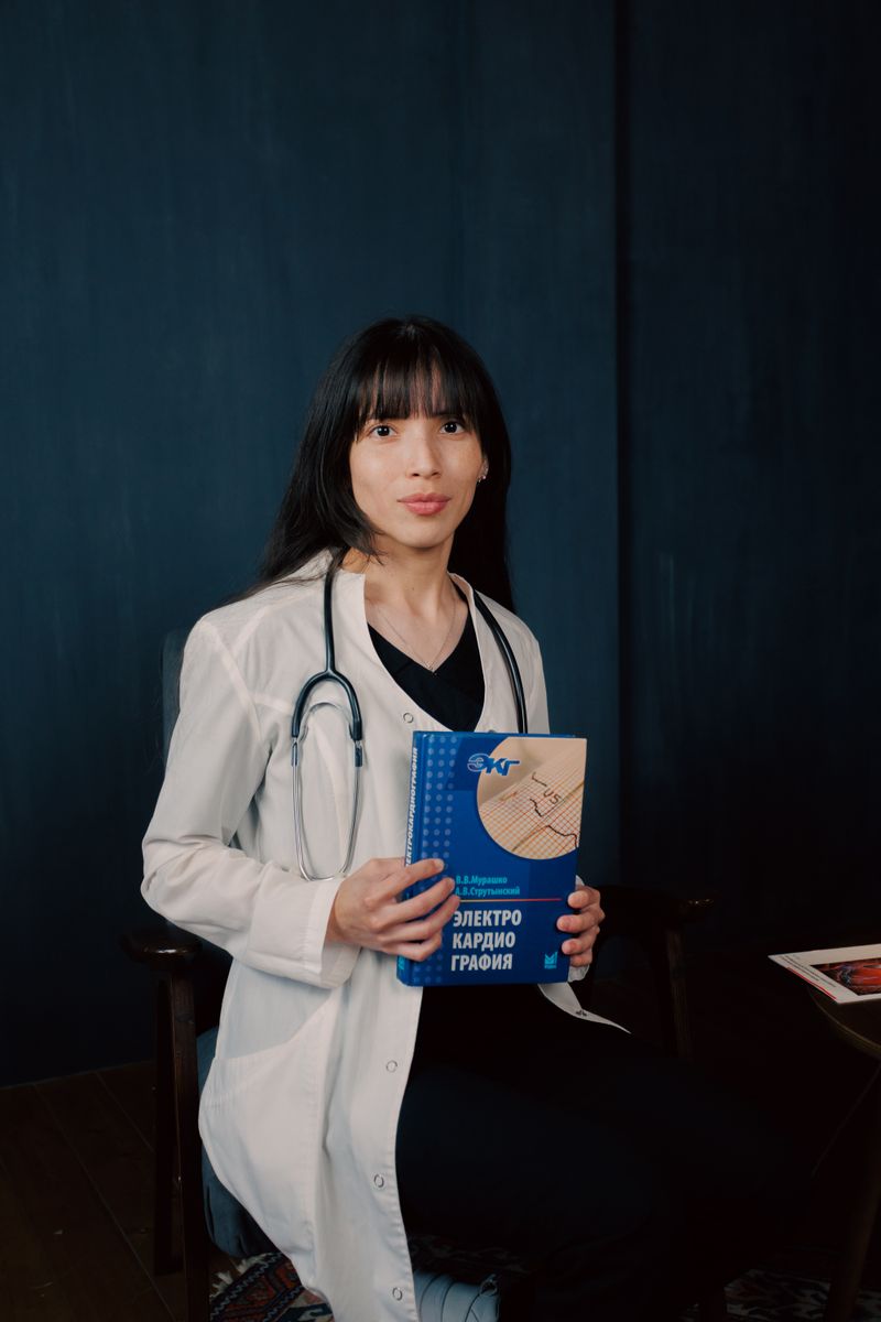 Young physician in a lab coat holding a reference book, stethoscope around her neck